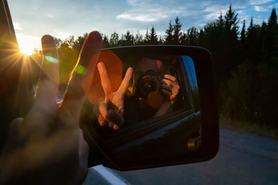 Reflection of man photographing car on side-view mirror