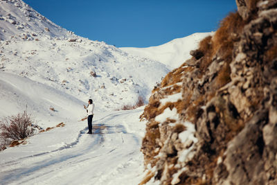 Woman standing against snowcapped mountain