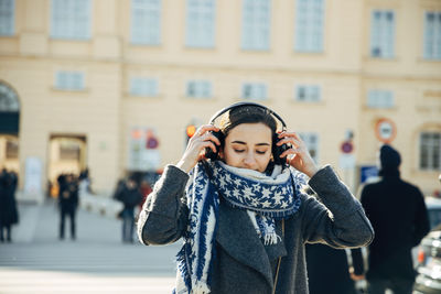 Young woman listening music on street in city