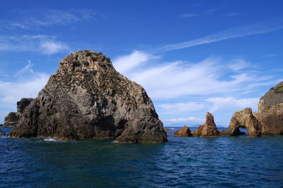 Rock formations in sea against blue sky