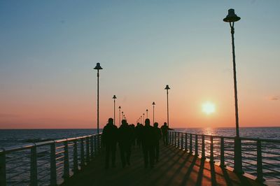 Silhouette people on pier against clear sky during sunset