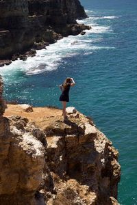 High angle view of woman standing on cliff by sea