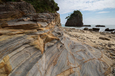 Rock formation on beach against sky