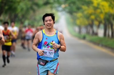 Portrait of smiling boy running on road in city