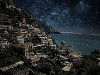 High angle view of townscape by sea against sky at night