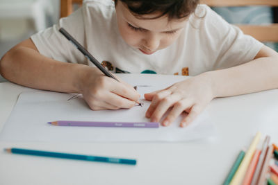 The boy draws with pencils at the kitchen, closeup. high quality photo