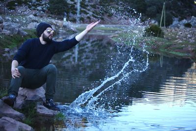 Man splashing water in lake at forest