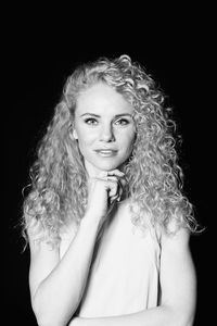 Portrait of woman with curly hair against black background