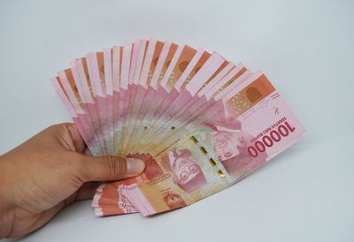 Close-up of person holding paper against white background