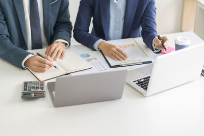 Rear view of people using laptop on table