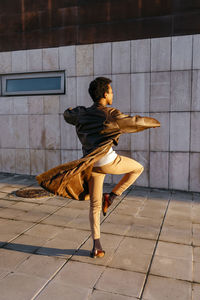 Man spinning while practicing dance against building