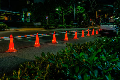 Road sign by illuminated street in city