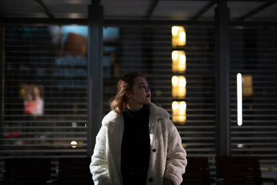 Young woman standing in city during winter at night