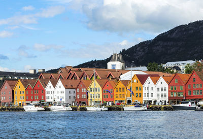 Houses by river and buildings against sky