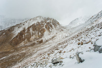 Scenic view of snow covered mountains against cloudy sky