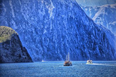 Boats in milford sound against mountains