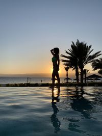 Silhouette man standing by sea against clear sky during sunset