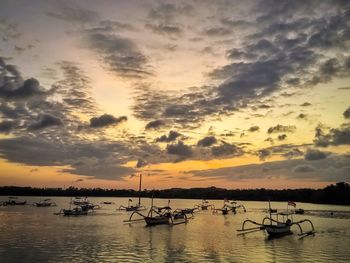 Silhouette boats moored in sea against sky during sunset