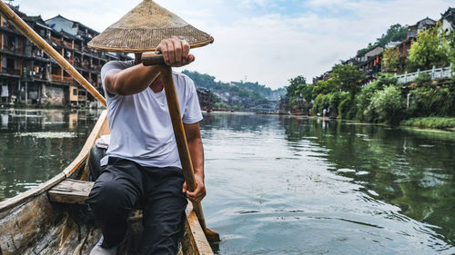 Rear view of man with hat on lake against sky