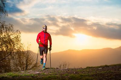 Man standing on land against sky during sunset