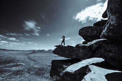 Man standing on rock against sky