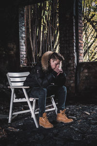 Man sitting on chair against trees