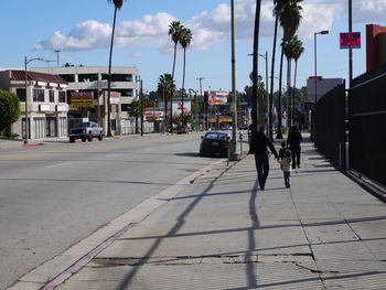 Rear view of family walking on sidewalk