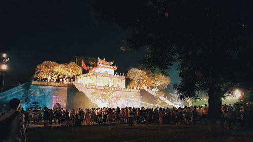 Crowd at illuminated city against sky at night