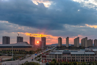 Buildings in city against sky during sunset