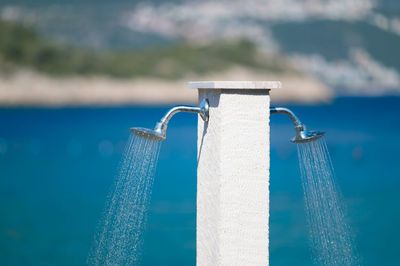 Close-up of showers by blue sea