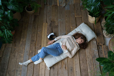 Calm woman with vr glasses headset lying on floor surrounded by plants rest after watching 3d video