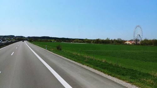 Road amidst field against clear sky