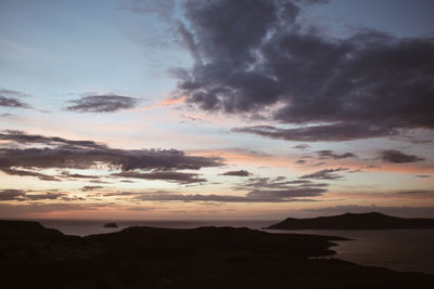 Scenic view of dramatic sky over silhouette mountains during sunset