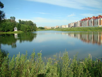 Scenic view of lake by buildings against sky