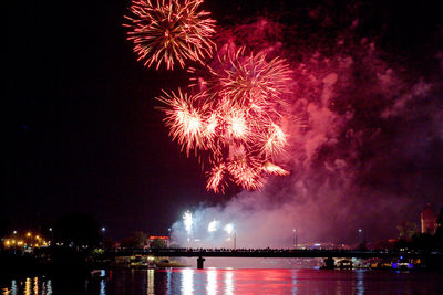 Firework display over river against sky at night