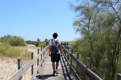 Rear view of woman walking on footbridge