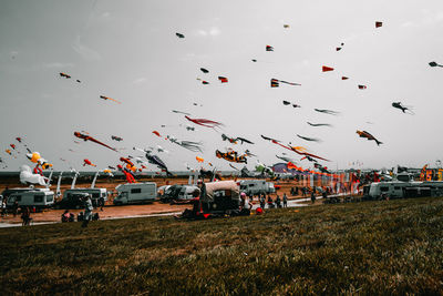 Low angle view of colorful kites flying over landscape against sky