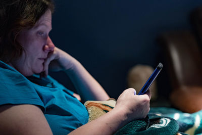 Side view of mature woman using phone at home
