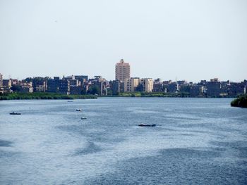 Sea by buildings against clear sky