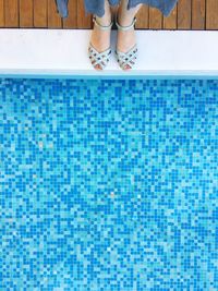 Low section of woman standing by swimming pool