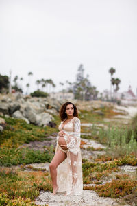 Portrait of beautiful young woman on land against sky