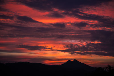 Scenic view of silhouette mountains against orange sky