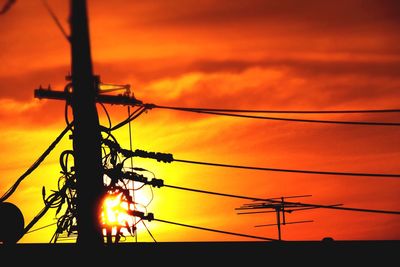 Low angle view of silhouette electricity pylon against sky during sunset