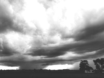 Silhouette trees on field against sky