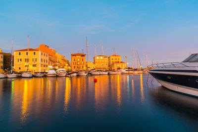 Boats moored at harbor against sky during sunset