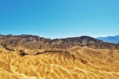 Scenic view of arid landscape against clear blue sky