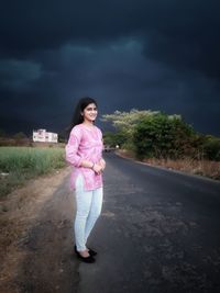 Portrait of woman standing on road against sky