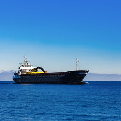 Sailboat sailing on sea against clear blue sky