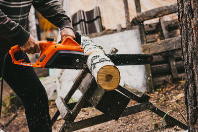 A man is sawing a trunk of a birch with a circular saw in the forest