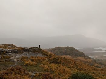 Man standing on mountain against sky in ireland